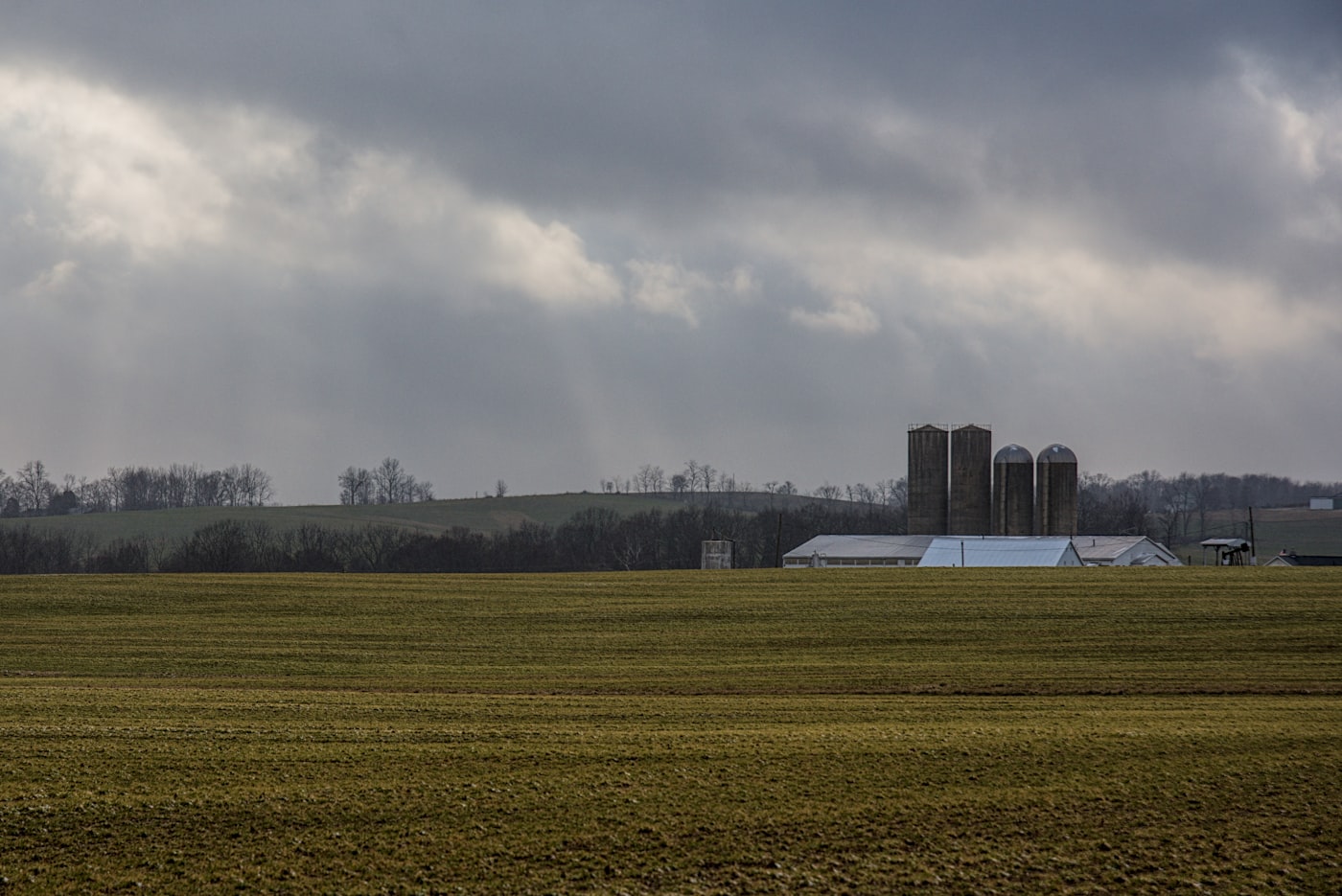 Wirtschaftsgebäude und Lagerbehälter eines landwirtschaftlichen Betriebs unter bewölktem Himmel